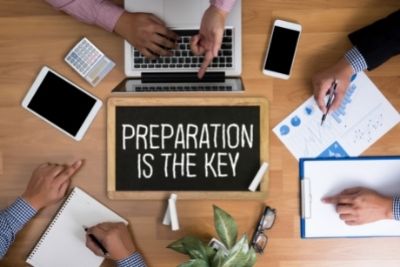 people round desk sign saying preparation is key